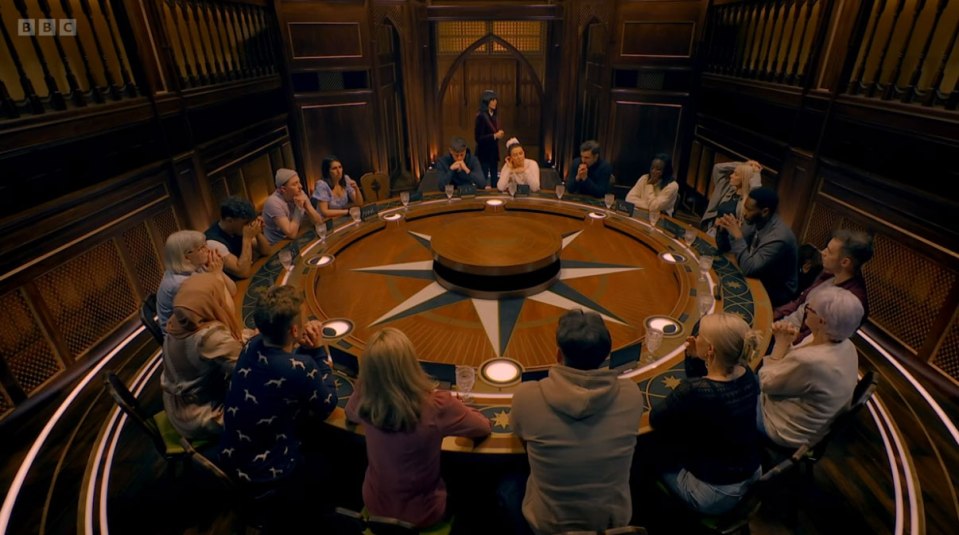 The Traitors contestants seated around a circular table.