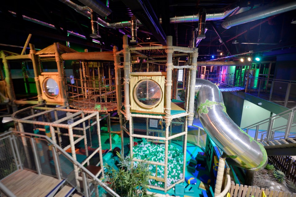 Indoor playground with a large metal slide and climbing structures.