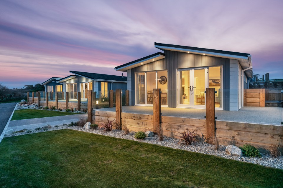 Two modern holiday park homes at dusk.