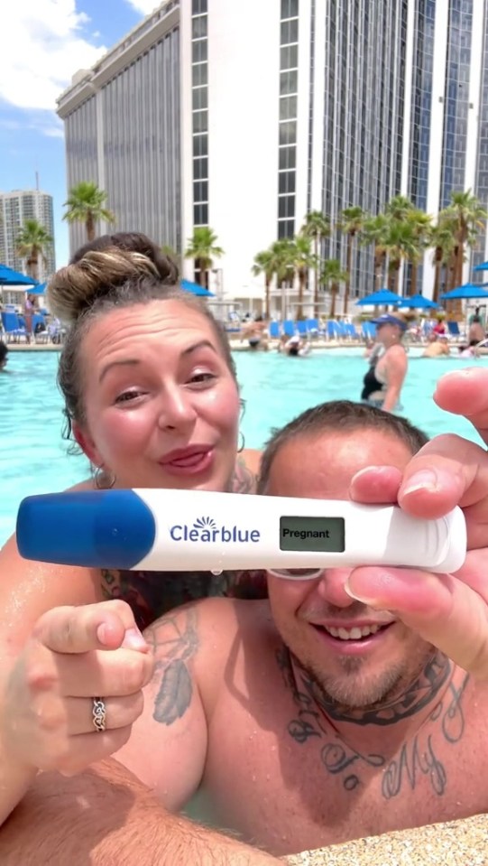 Couple by a pool holding a positive pregnancy test.