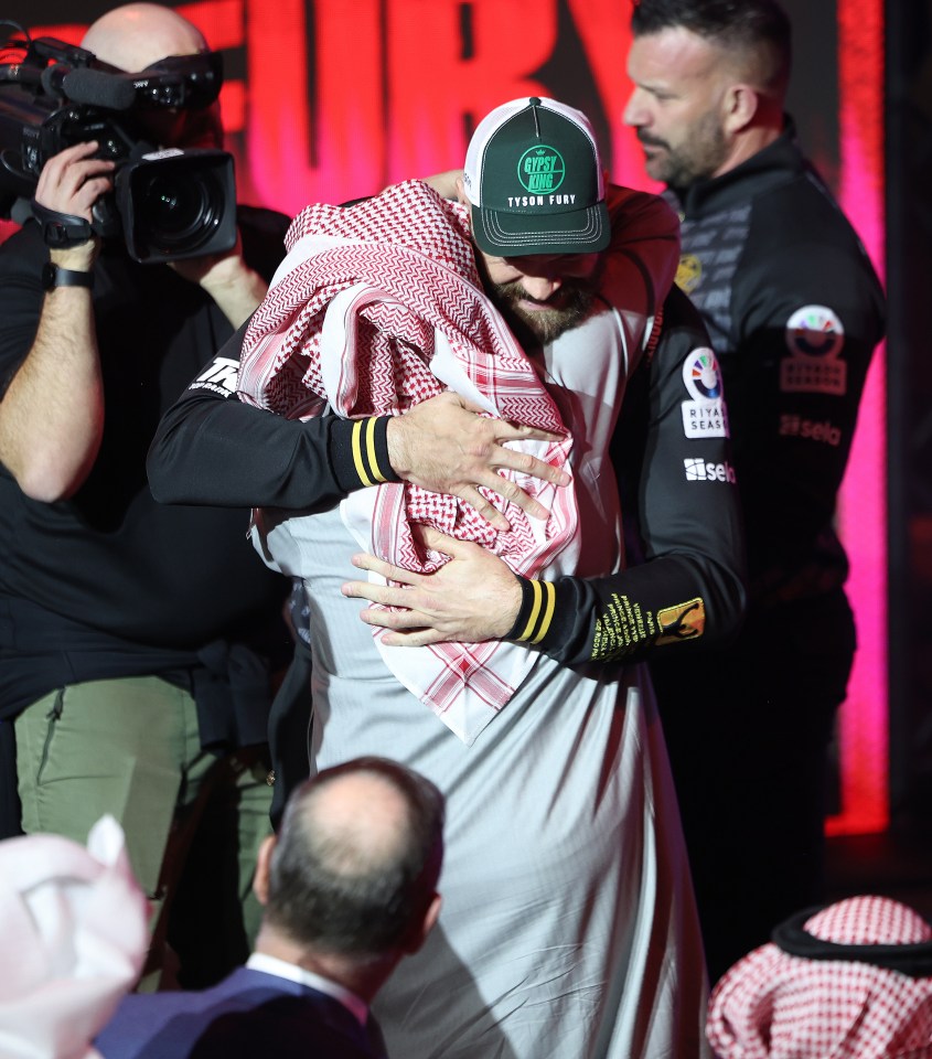 Tyson Fury hugging a man in traditional Saudi Arabian clothing.