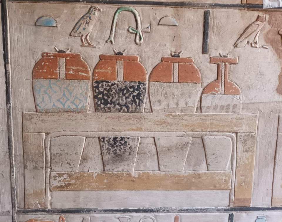 Colorful reliefs depicting jars and birds on a Saqqara mastaba wall.