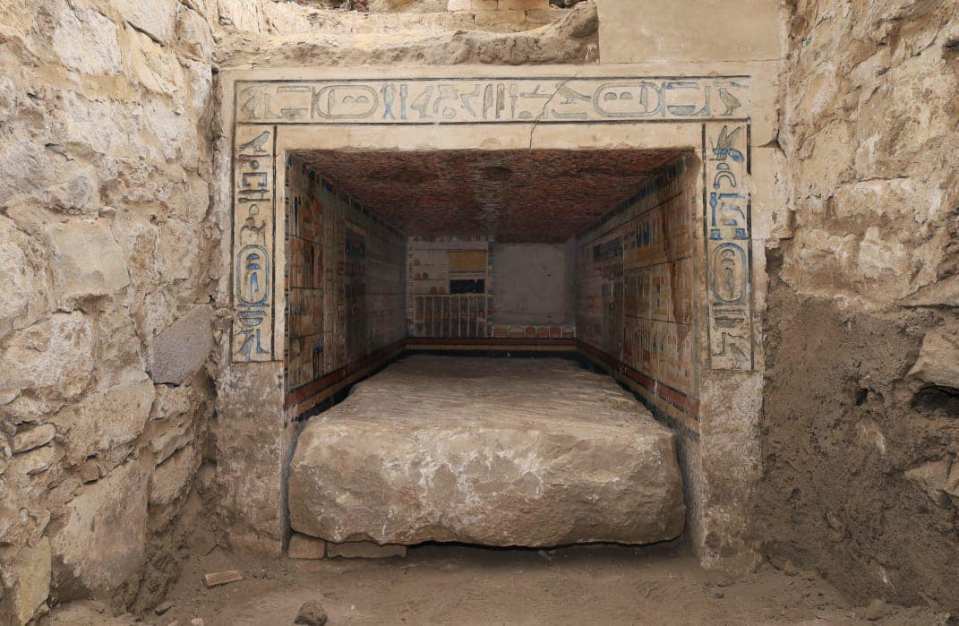 Interior of a 4,000-year-old mastaba at Saqqara, Egypt, showing colorful reliefs and a large stone slab.