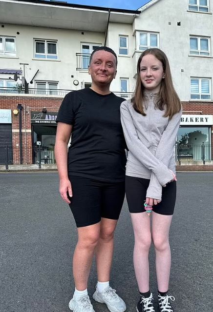 A woman and a girl standing outside a building.