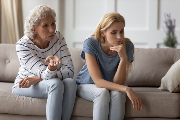 An older woman talks to a younger woman who is sitting on a couch and looking down.