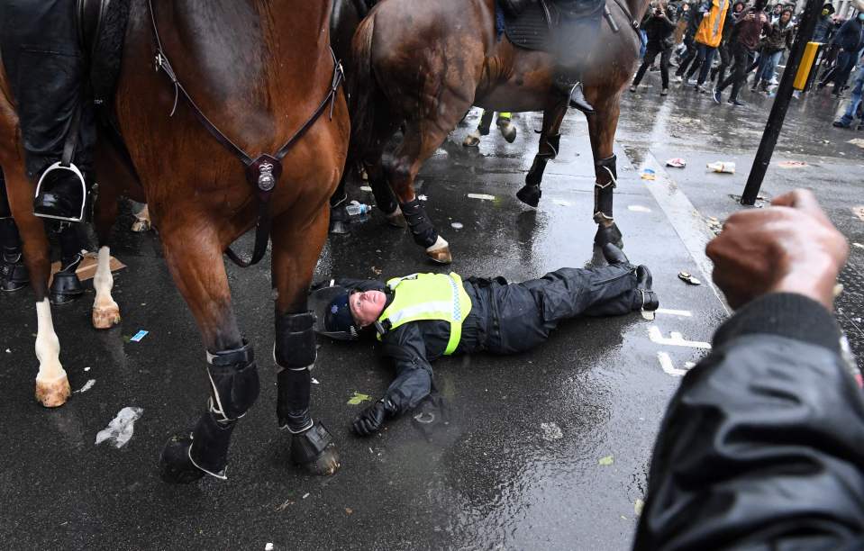 The officer was thrown from the saddle as thugs hurled flares and fireworks