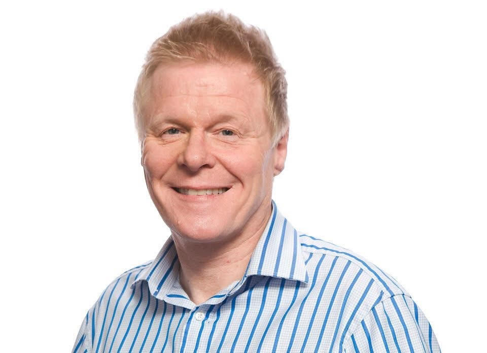 Portrait of a smiling man with blond hair wearing a blue and white striped shirt.