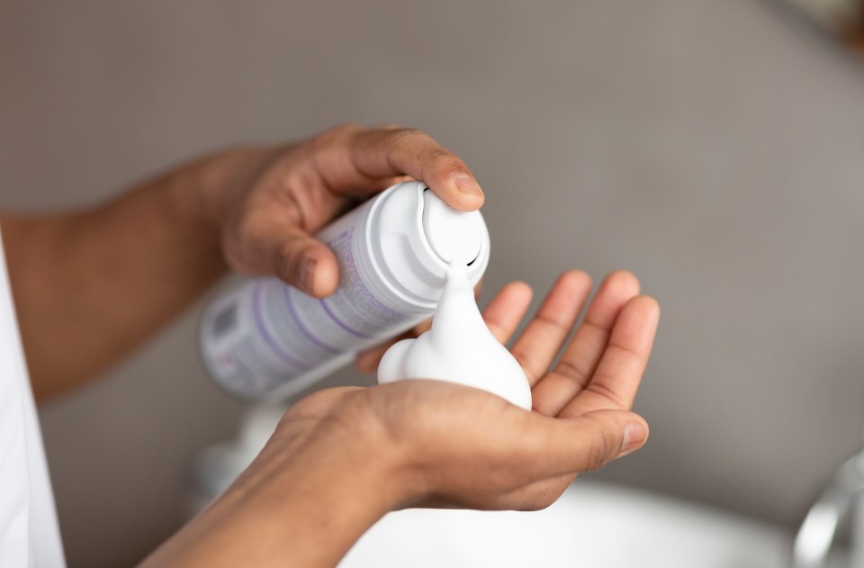 Person dispensing shaving cream onto their hand.