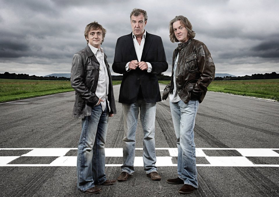 Richard Hammond, Jeremy Clarkson, and James May of Top Gear standing on a racetrack.