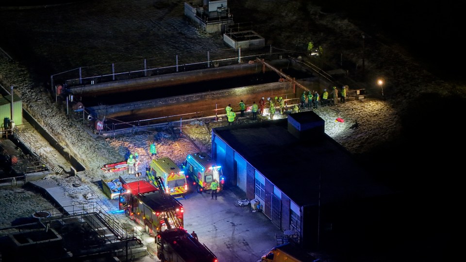 Aerial view of emergency responders at a sewage treatment plant at night.