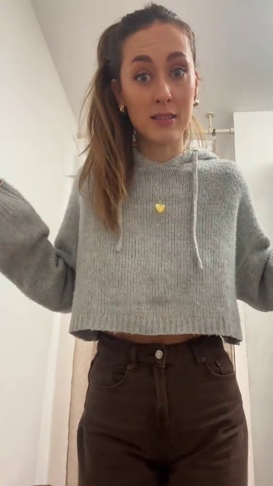 Woman in gray sweater and brown pants.