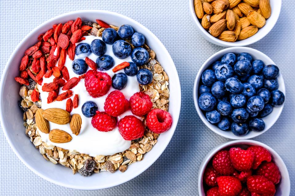 Healthy vegetarian breakfast bowl with muesli, yogurt, berries, nuts, and goji berries.