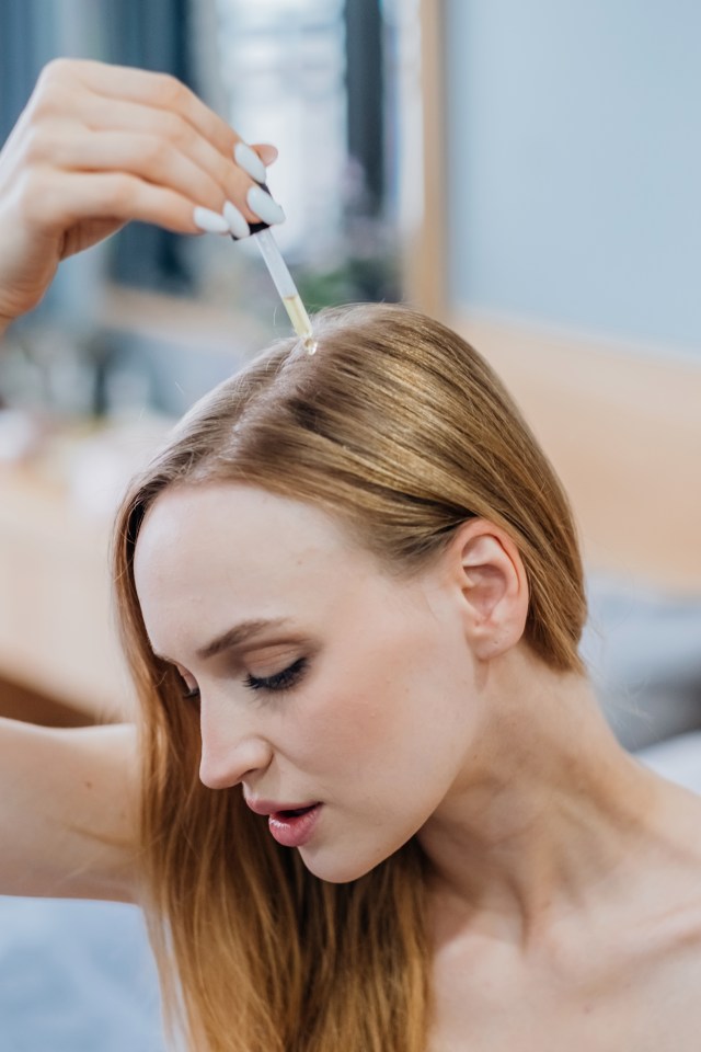 Woman applying hair oil with a pipette.