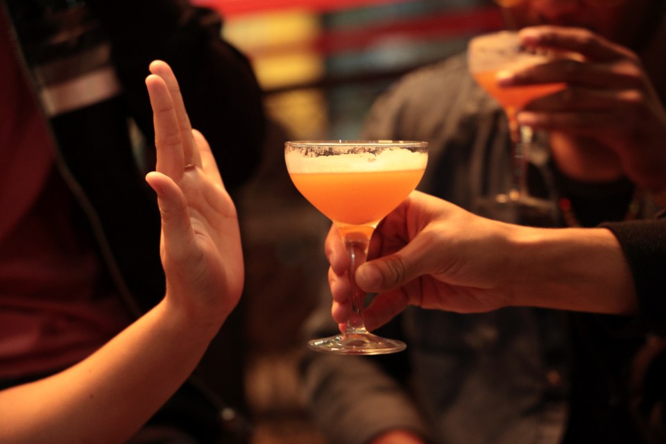 Woman refusing a drink at a bar.