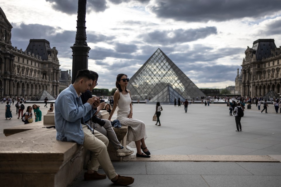 Woman posing in front of the Louvre Pyramid in Paris.