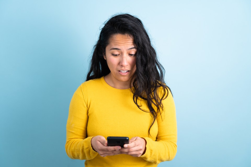 Woman looking sad while reading her phone.