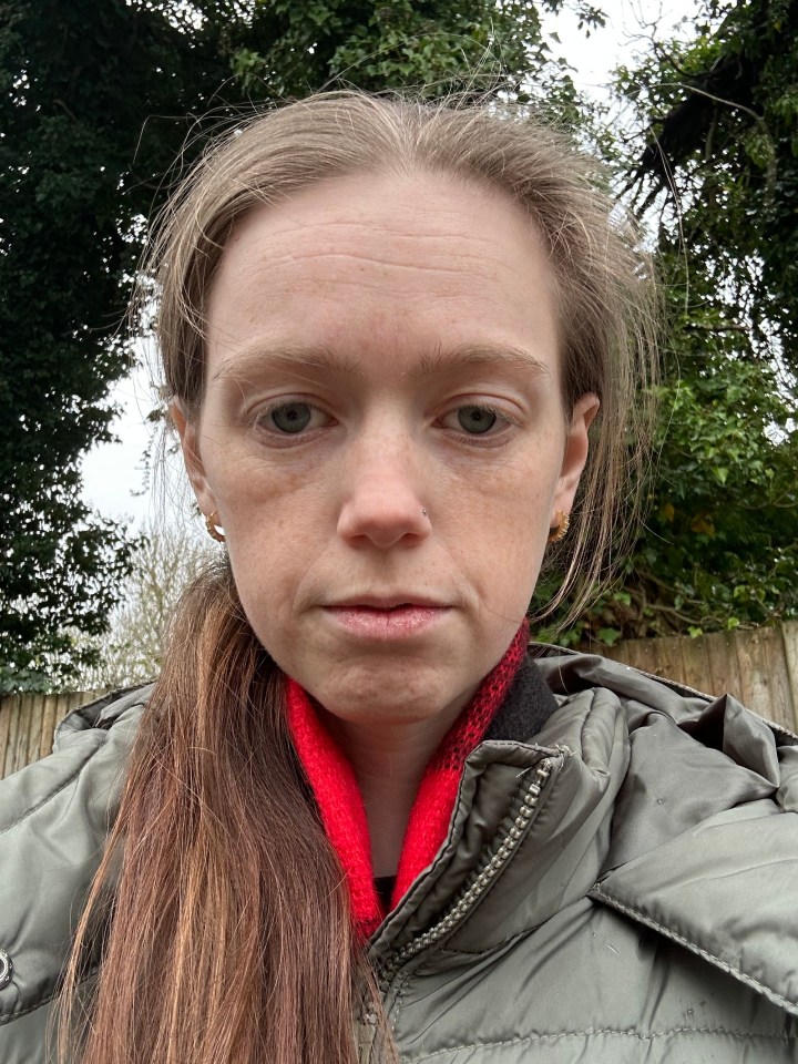 Woman with long brown hair wearing a green jacket and red scarf.