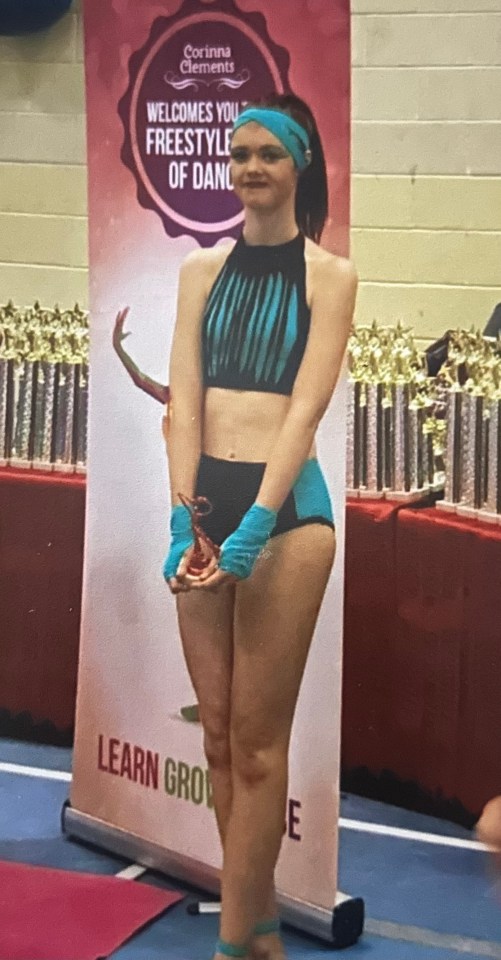 A young woman in a dance costume holding an award.