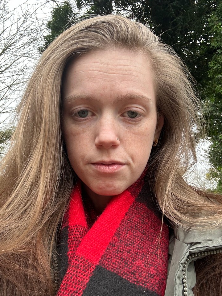 Woman with long brown hair wearing a red and black scarf.