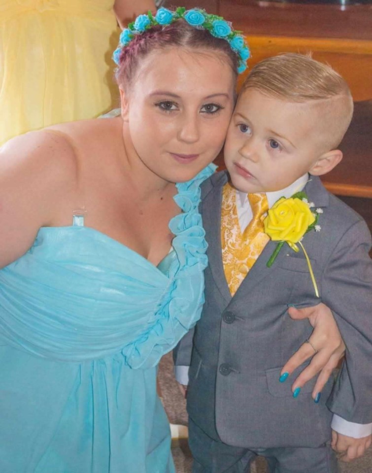 Woman in a light blue dress and a young boy in a gray suit.