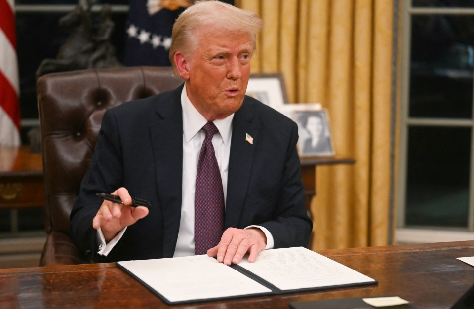 President Trump signing an executive order in the Oval Office.