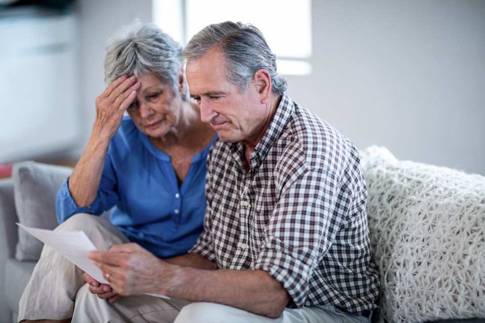 Worried senior couple reviewing bills.