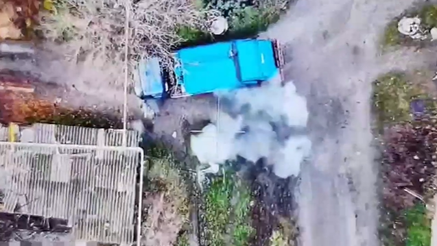 Aerial view of a blue vehicle emitting smoke.