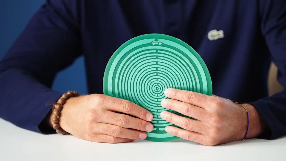 Person holding a green circular disc with concentric circles.