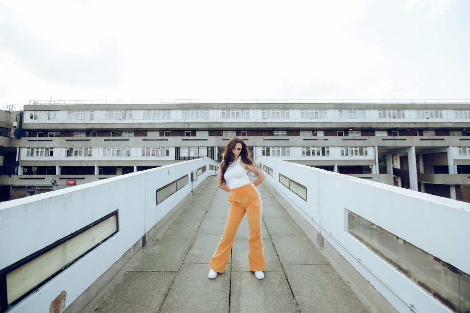 Cher Lloyd on a walkway in front of a building.