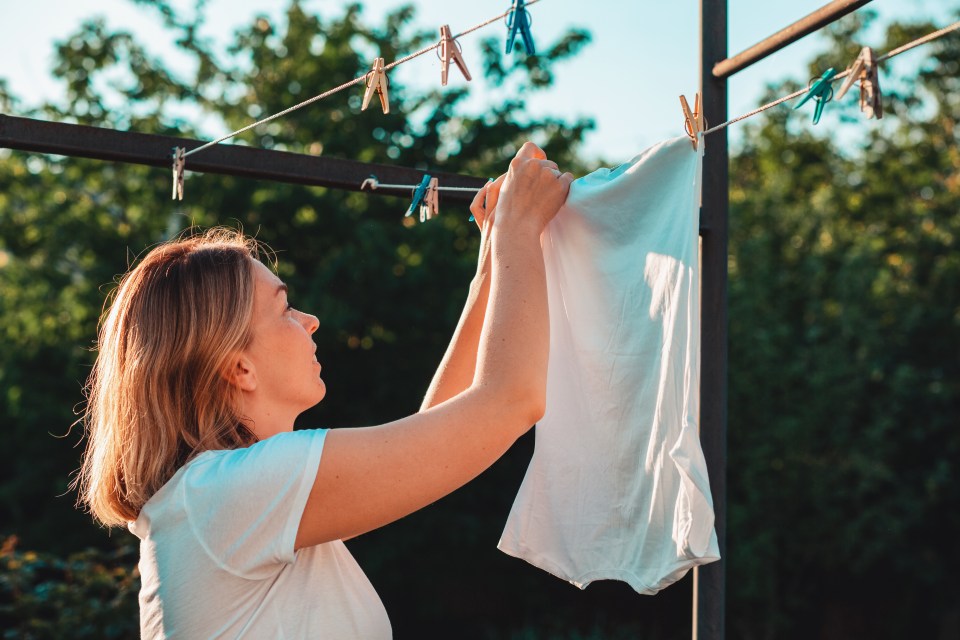 Woman hanging laundry outside.