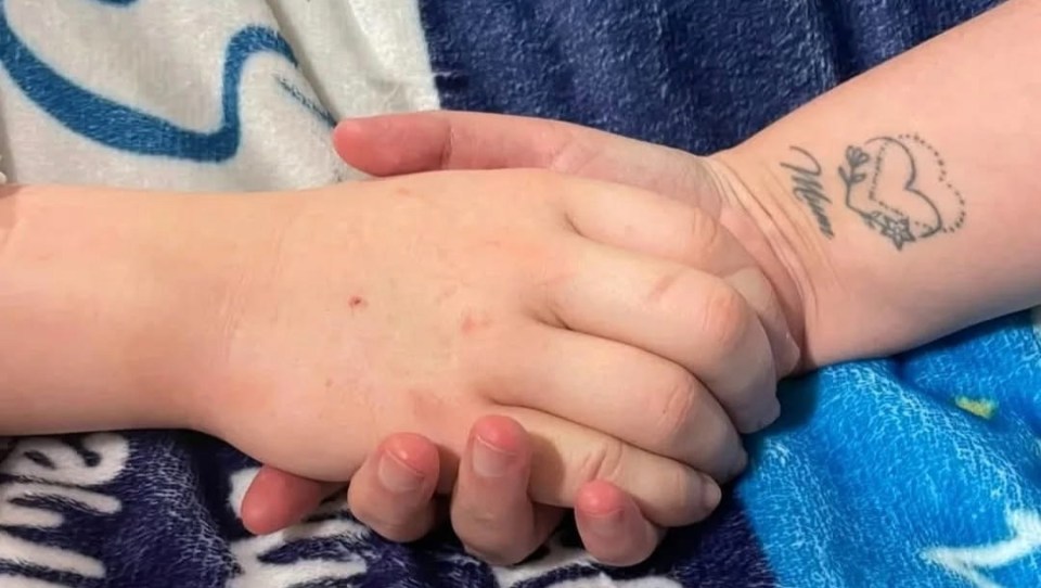 A mother holding her deceased son's hand.