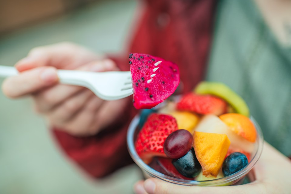 Woman eating a fruit salad outdoors.