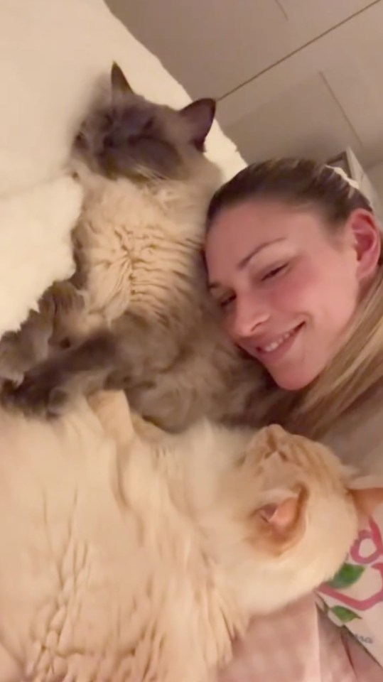 Woman cuddling with two cats.