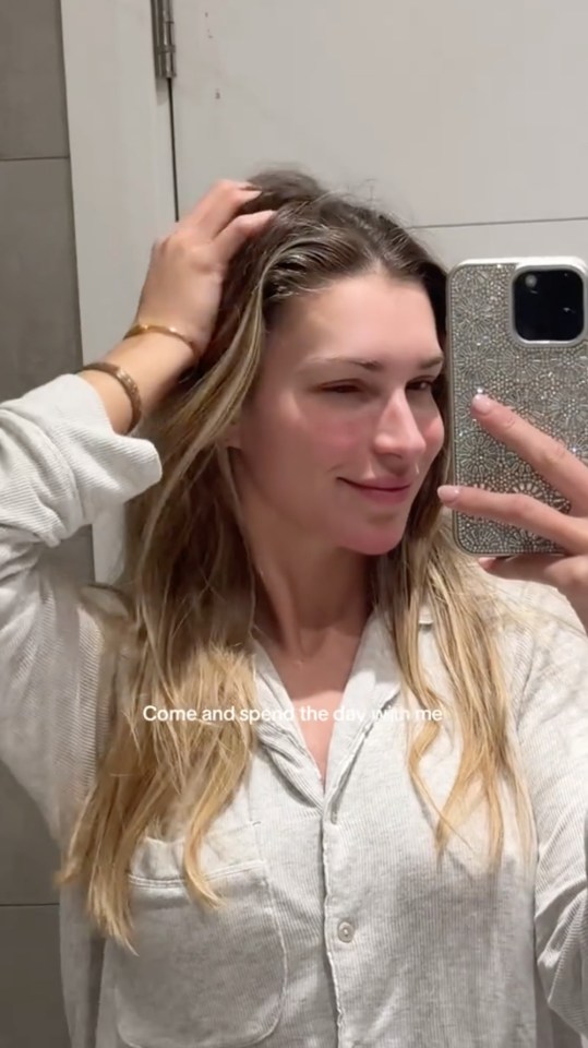 Zara McDermott in a selfie video, wearing a grey shirt, inviting viewers to spend the day with her.