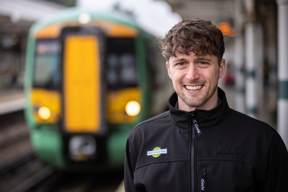 Portrait of a smiling train driver in front of a train.