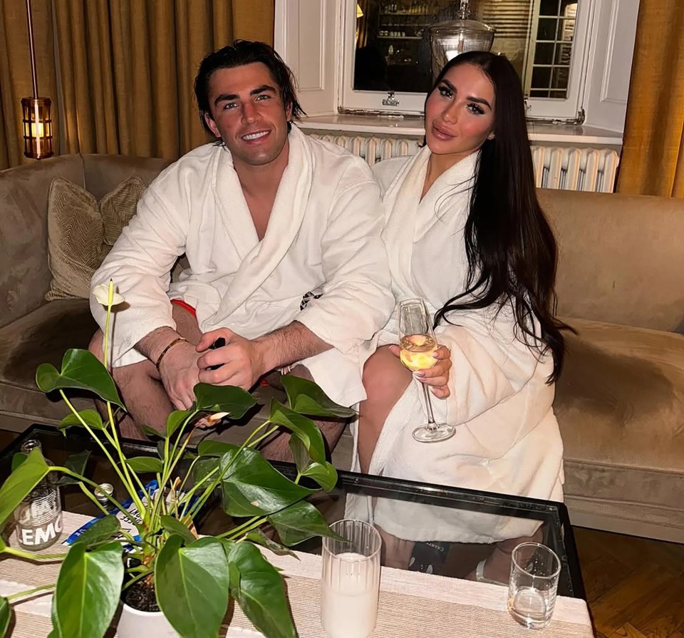 Jack Fincham and Chloe Brockett in bathrobes, enjoying champagne.