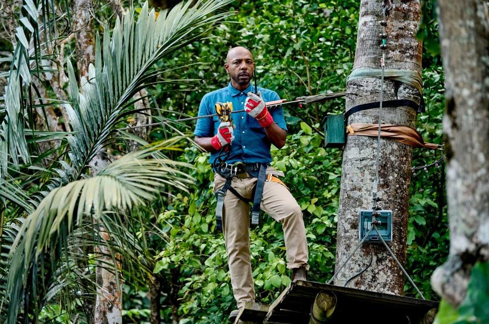 Man attaching zip line in rainforest.