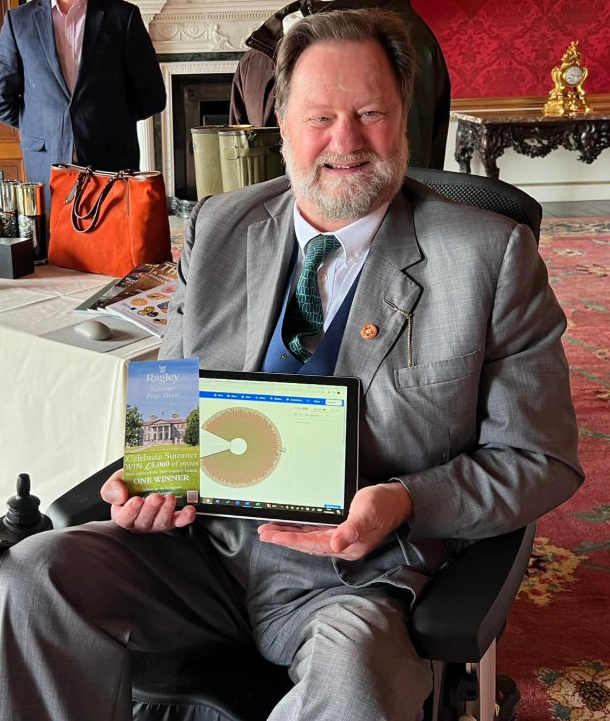 Lord Hertford holding a tablet and a brochure.