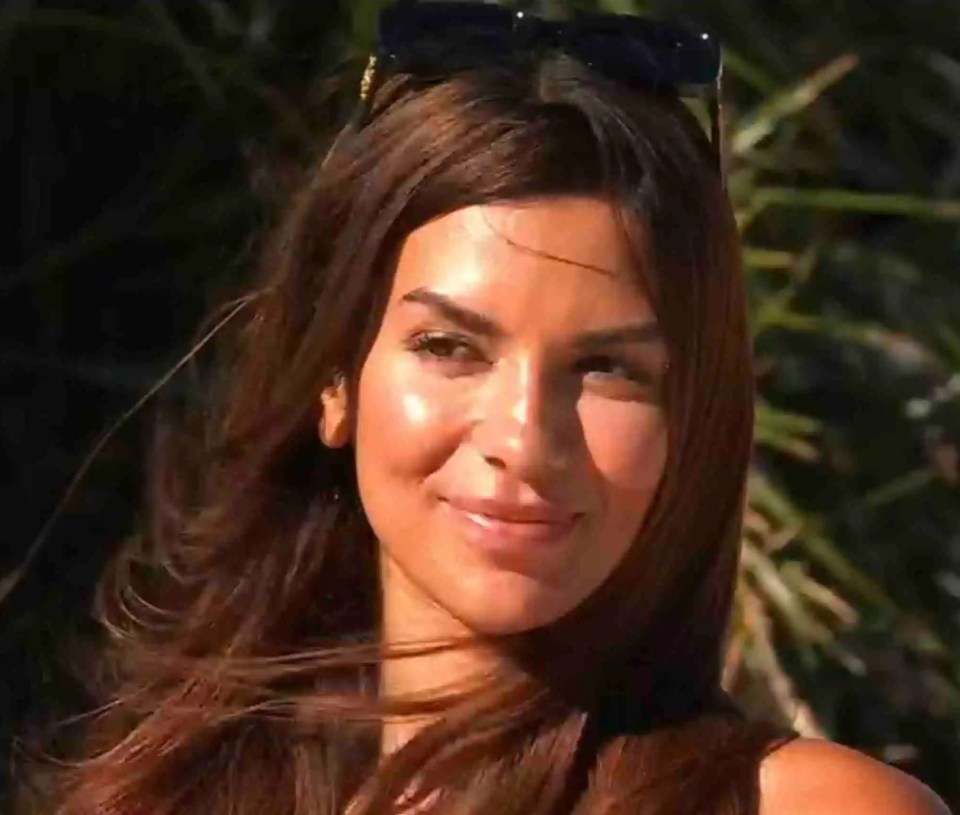 A woman with long brown hair smiles outdoors.