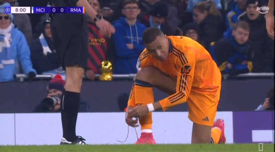 Soccer player tying his shoelace on the field.