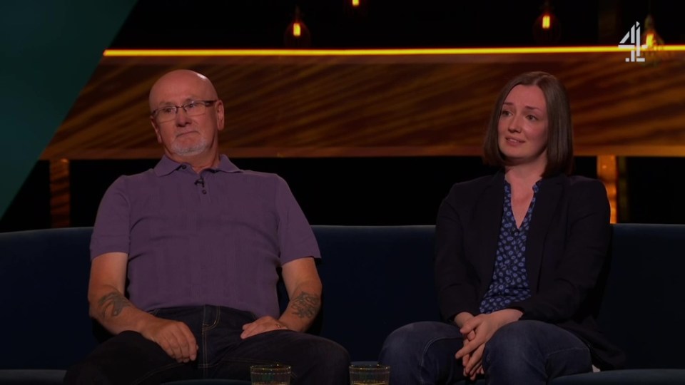 A man and a woman sitting on a couch, appearing emotional.