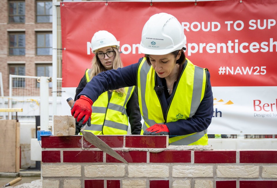 Secretary of State for Education laying bricks at a construction site.