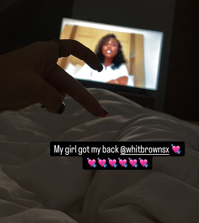 Hand gesture in front of a TV screen showing a woman; text overlay reads "My girl got my back @whitbrownsx".