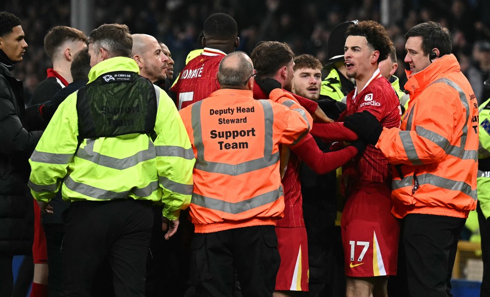 Liverpool's Curtis Jones being held back by stewards after a football match.