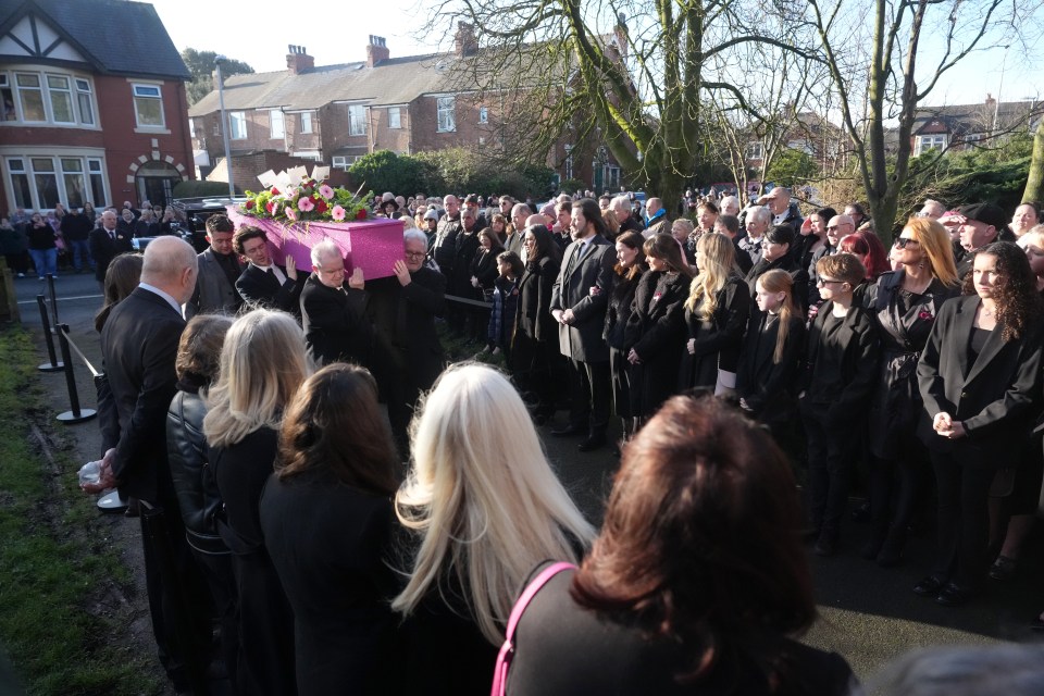 Pallbearers carry a pink coffin at a funeral.