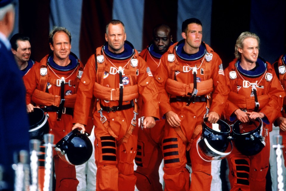 Still from the film Armageddon showing Bruce Willis and other actors in orange spacesuits.