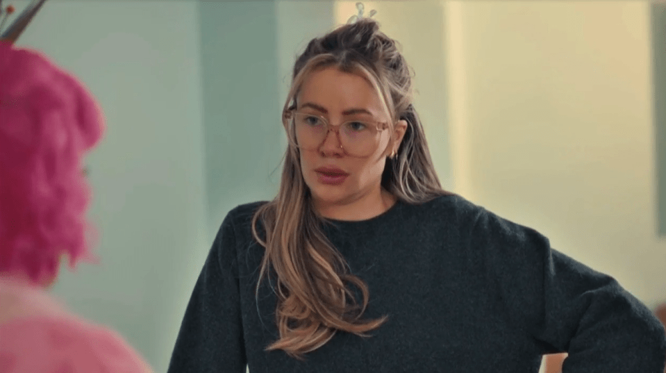 Woman with long blonde hair and glasses in conversation.