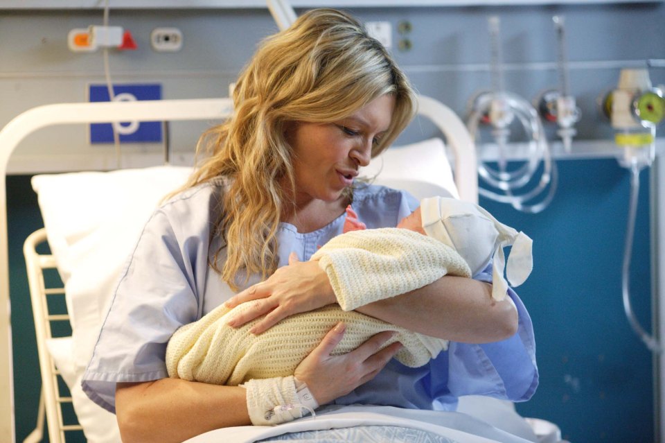 A mother holding her newborn baby in a hospital room.