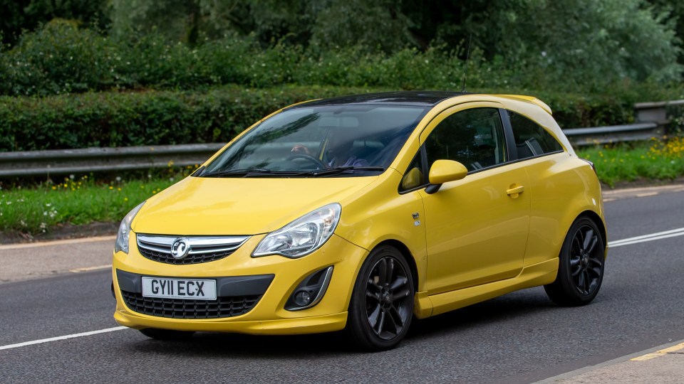 Yellow Vauxhall Corsa driving on a road.