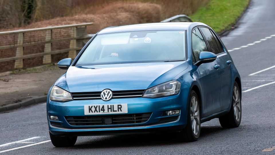 Blue Volkswagen Golf driving on a road.